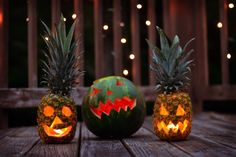 two pineapple pumpkins with faces carved into them sitting on a wooden table in front of string lights