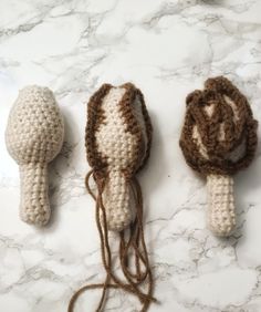 three crocheted objects are sitting on a marble surface, one is brown and the other is white