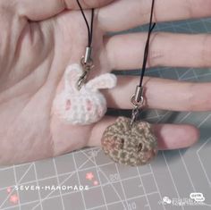 someone is holding two tiny crocheted items in their hands, one has a small keychain on it