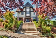 a large house with stairs leading up to the front door and trees lining the street