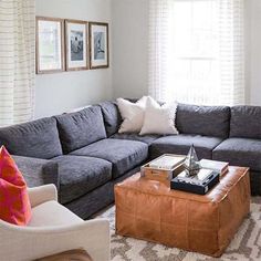 a living room with gray couches and white curtains on the window sill,