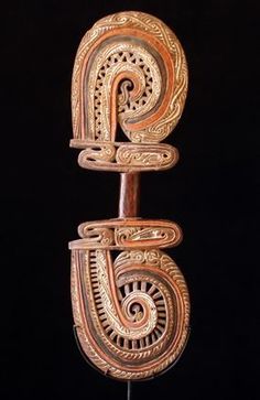 an intricately carved wooden object on a black background with the letter g in it's center