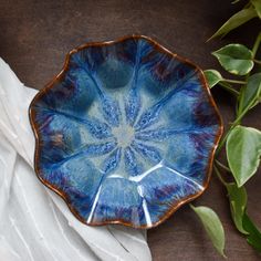 a blue bowl sitting on top of a wooden table next to leaves and napkins