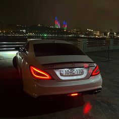 the rear end of a car parked in front of a cityscape at night