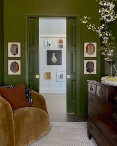 a living room with green walls and pictures on the wall