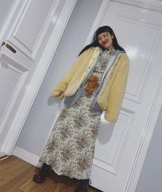 a woman standing in front of a white door wearing a dress and jacket with a teddy bear on it