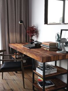 a wooden desk topped with books next to a window