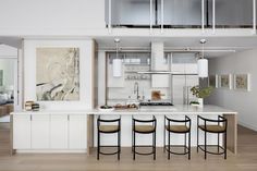 a kitchen with an island and four stools in front of the counter top area