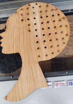 a wooden cutout of a woman's head with holes in it