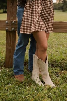 a man and woman standing next to each other in front of a wooden fence holding hands