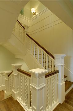 a white staircase with wooden handrails next to a banister in a house