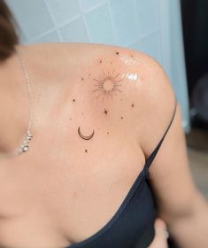 a woman with a sun and moon tattoo on her upper arm, behind her shoulder