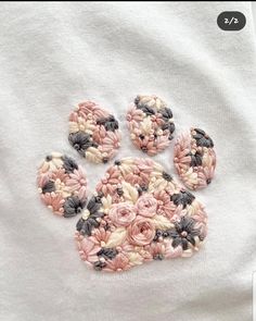 four crocheted flowers sitting on top of a white t - shirt with black and pink trim