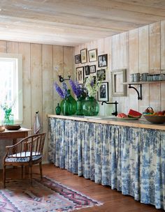 a kitchen with pictures on the wall and flowers in vases