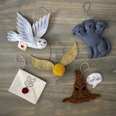 four ornaments are arranged on a wooden surface, including an owl, cat and bird ornament