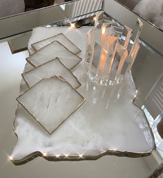 a glass table with candles on it and some mirrors in the back ground behind it