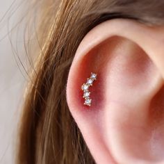 a woman's ear with three small diamonds on it