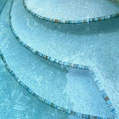 an empty swimming pool with tiled steps leading up to the water's edge and blue tiles on the floor