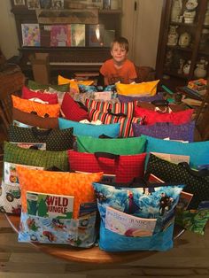 a young boy sitting in front of a pile of pillows on top of a table