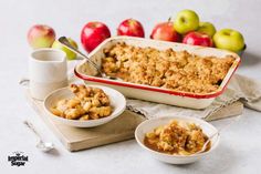 an apple crumbler with two bowls of apples in the background