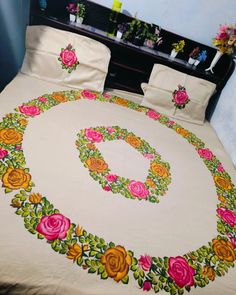 a bed covered in a white bedspread with pink and yellow flowers on it