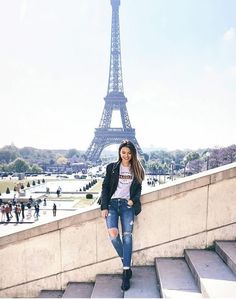 a woman is standing on some steps in front of the eiffel tower, paris