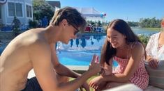 two people sitting next to each other near a pool