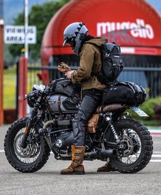 a man sitting on the back of a motorcycle while looking at his cell phone in front of a mcdonald's