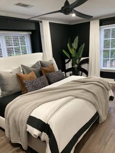 a bedroom with black walls, white bedding and wooden flooring is pictured in this image