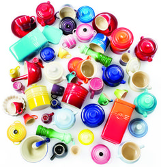 a pile of colorful cups and saucers on a white surface with the lid off