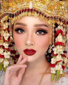 a woman with red lipstick and gold jewelry wearing a headdress that has flowers on it