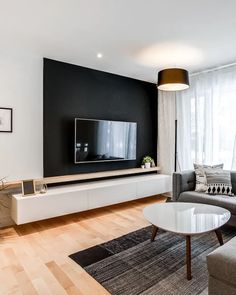 a modern living room with black and white walls, wood flooring and large television on the wall