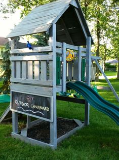 a wooden play structure with a slide in the grass