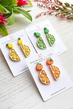 three brooches with fruits and vegetables on them sitting on a table next to flowers