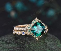 an emerald colored stone surrounded by diamonds on top of a rock