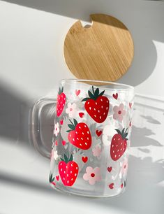 a glass cup with strawberries on it and a wooden spoon hanging from the side