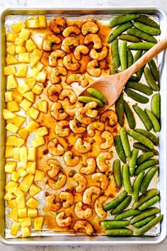 sheet pan with shrimp, pineapples and snap peas on it in the process of cooking