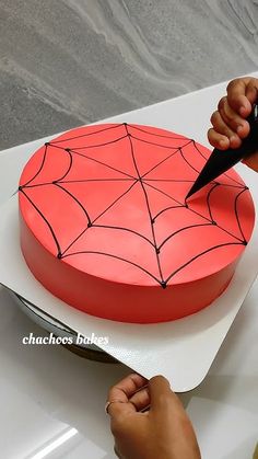 a person cutting into a cake with a knife and spider web decoration on it's side