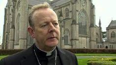 a man wearing a priest's outfit standing in front of a church