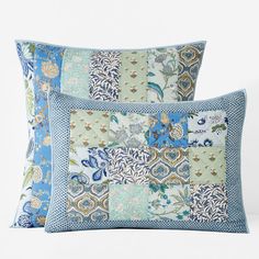 two blue and green patchwork pillows sitting next to each other