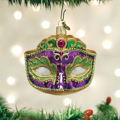 a mardi gras mask ornament hanging from a christmas tree