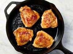 three pieces of chicken in a skillet on a marble counter top, ready to be cooked