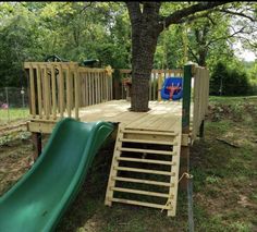 a wooden play area with a slide and tree