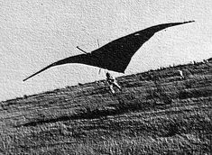 a man flying a large kite on top of a grass covered field