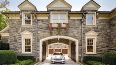 a car is parked in front of a large house with stone walls and arched doorways