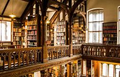 the inside of a library with lots of books on shelves and many windows in it