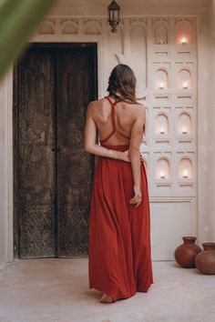 a woman standing in front of a door wearing a red dress and looking down at the floor