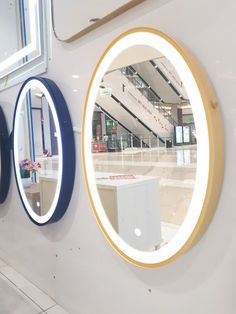 three round mirrors mounted to the side of a wall next to a white tiled floor