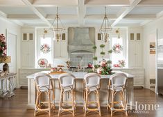 a large kitchen with white cabinets and wooden floors is decorated with christmas wreaths on the windows