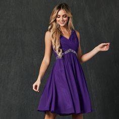 a woman in a purple dress posing for the camera with her hand out and smiling